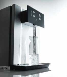 Wasserspender Eauvtion Acqua 80 füllt eine Glaskaraffe mit frischem Sprudelwasser