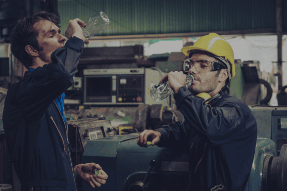 Zwei Arbeiter in einer Produktion trinken Wasser